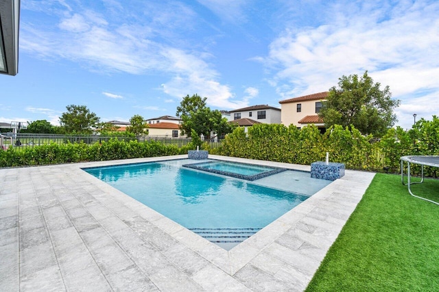 view of pool with an in ground hot tub, a yard, a patio, and a trampoline