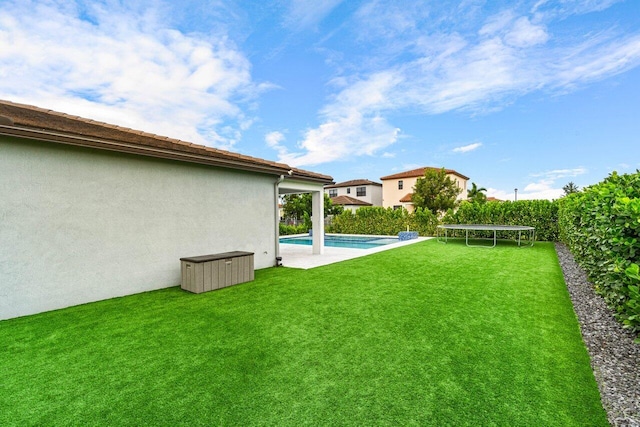 view of yard with a trampoline and a fenced in pool