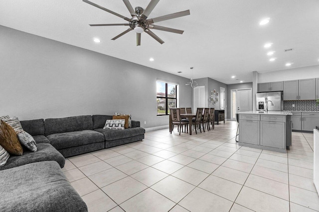 tiled living room with ceiling fan with notable chandelier