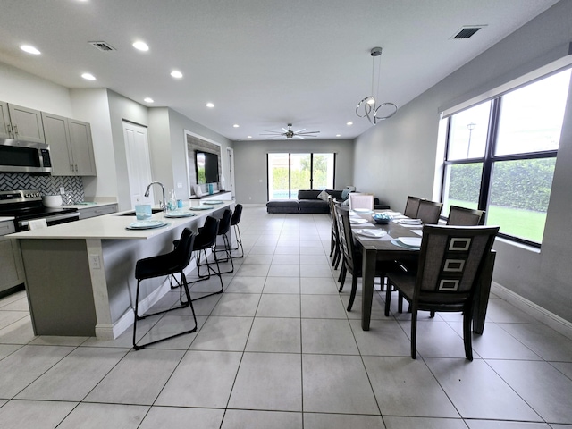 dining room featuring sink, light tile patterned floors, and ceiling fan with notable chandelier