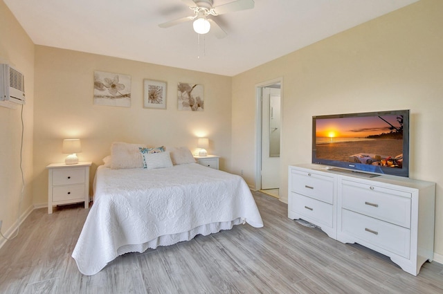 bedroom featuring ceiling fan, an AC wall unit, and light hardwood / wood-style floors