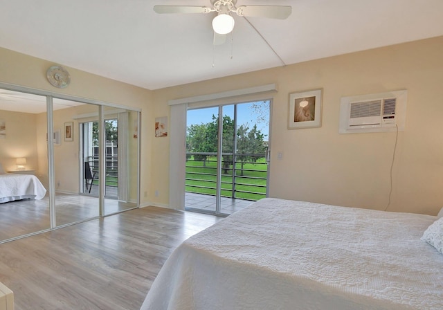 bedroom featuring a wall mounted air conditioner, light hardwood / wood-style flooring, access to exterior, and ceiling fan