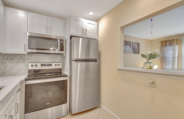 kitchen featuring white cabinetry, stainless steel appliances, backsplash, and light tile patterned floors