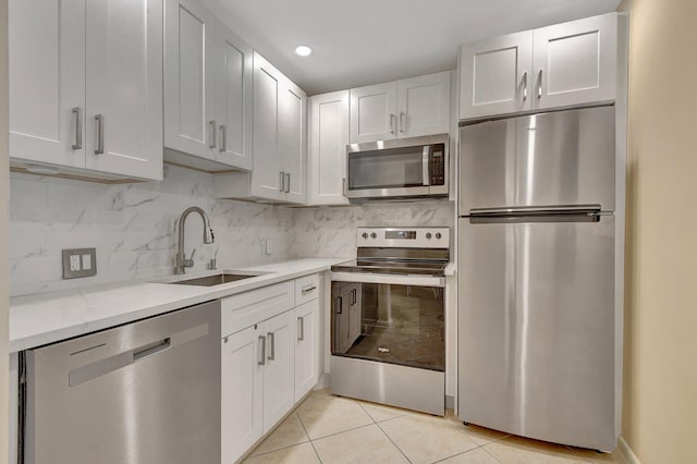 kitchen with light tile patterned floors, appliances with stainless steel finishes, sink, and white cabinets