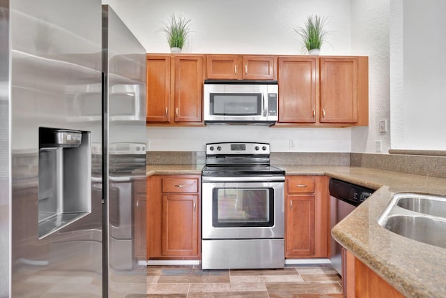 kitchen featuring light stone countertops, appliances with stainless steel finishes, and sink