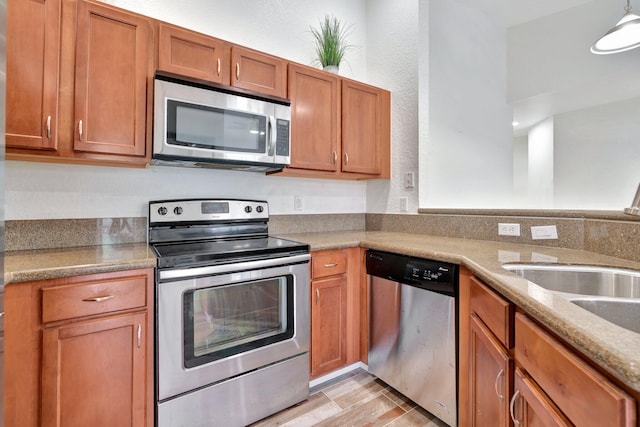 kitchen featuring light stone countertops, sink, stainless steel appliances, and light wood-type flooring