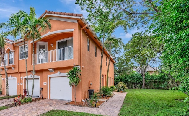 exterior space featuring a front yard, a balcony, and a garage