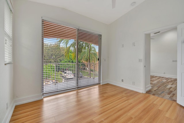 empty room with light hardwood / wood-style floors, lofted ceiling, and a wealth of natural light