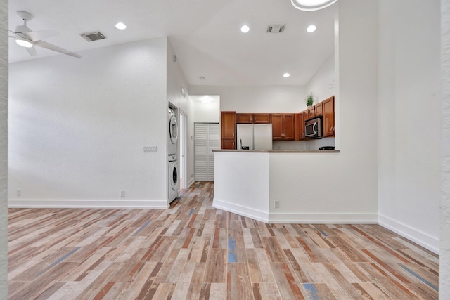 interior space with stacked washer and clothes dryer, vaulted ceiling, light hardwood / wood-style flooring, ceiling fan, and refrigerator with ice dispenser