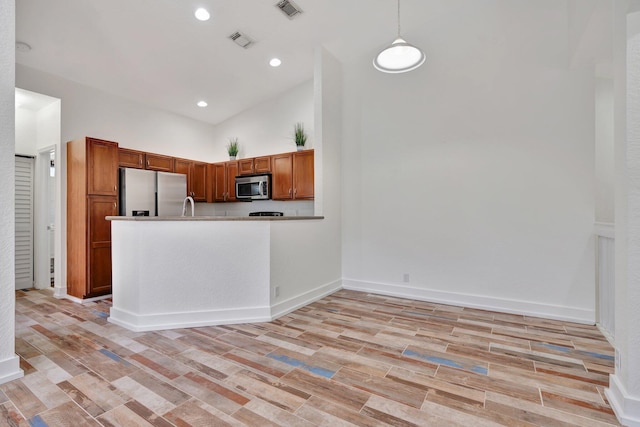 kitchen featuring hanging light fixtures, high vaulted ceiling, kitchen peninsula, appliances with stainless steel finishes, and light wood-type flooring