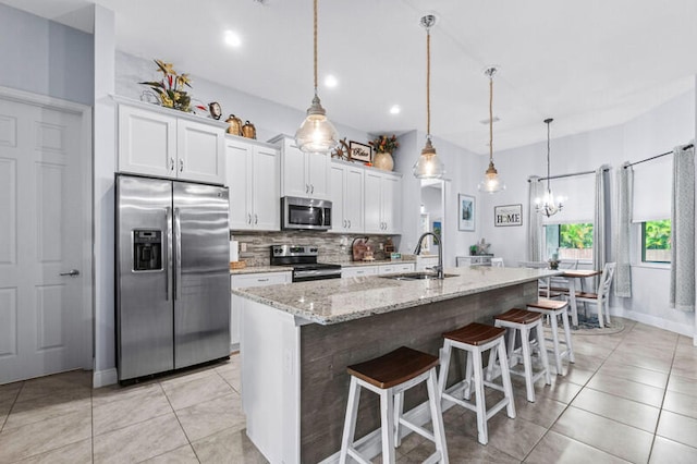 kitchen with white cabinets, a center island with sink, appliances with stainless steel finishes, a kitchen breakfast bar, and sink