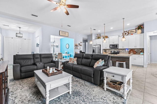 living room featuring ceiling fan with notable chandelier and light tile patterned floors