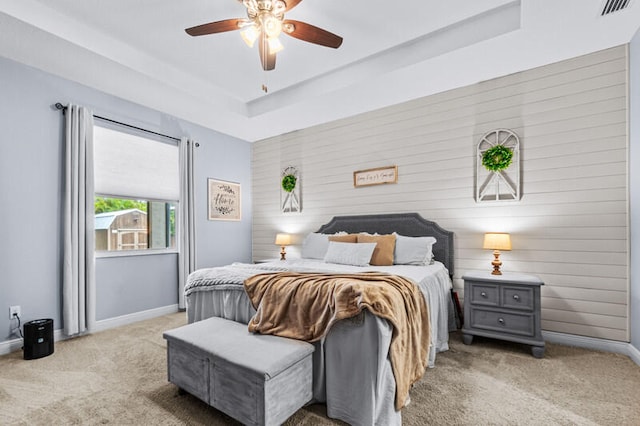 bedroom with ceiling fan, light carpet, and a raised ceiling