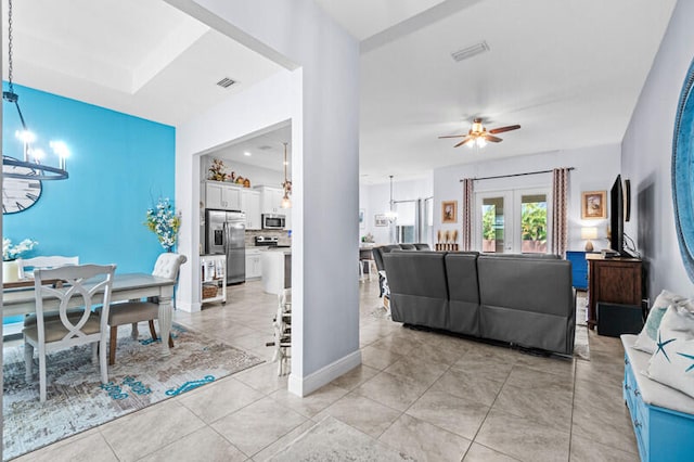 living room with french doors, ceiling fan with notable chandelier, and light tile patterned floors