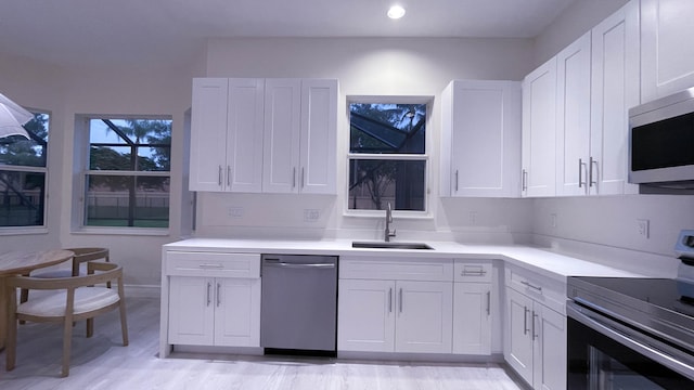 kitchen featuring white cabinetry, stainless steel appliances, sink, and light wood-type flooring