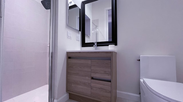 bathroom with vanity, toilet, and tiled shower