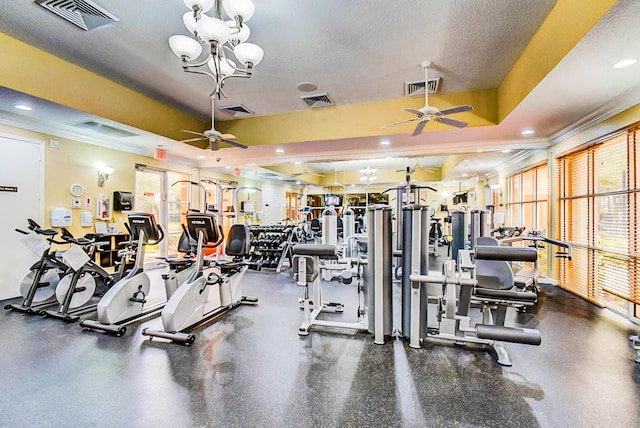 workout area with ornamental molding, a textured ceiling, ceiling fan with notable chandelier, and a raised ceiling