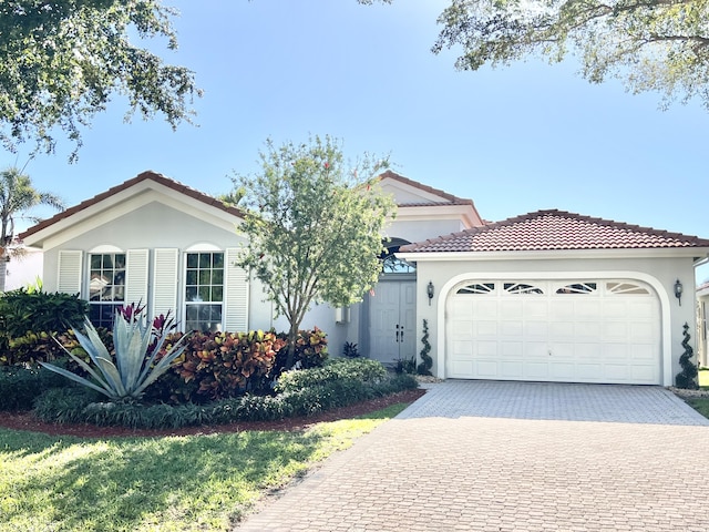 view of front facade featuring stucco siding, an attached garage, a tile roof, and decorative driveway