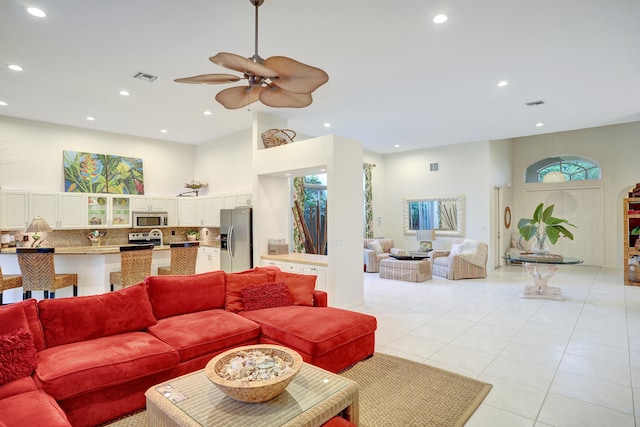 living room with ceiling fan, high vaulted ceiling, and light tile patterned floors