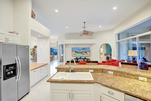 kitchen with sink, ceiling fan, stainless steel fridge, light tile patterned floors, and white cabinetry