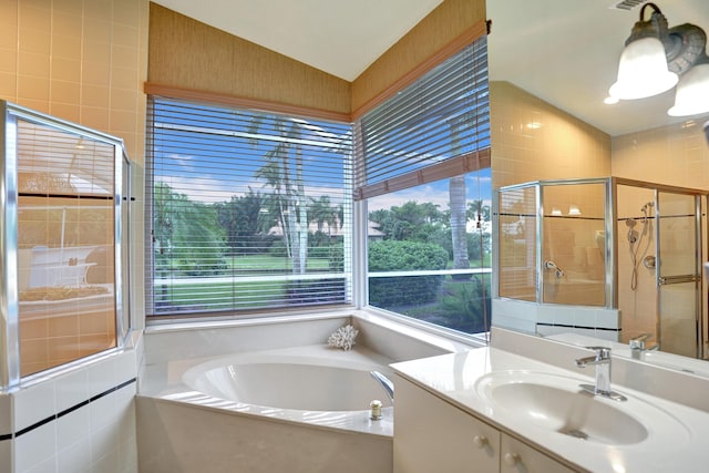 bathroom with vanity, shower with separate bathtub, and tile walls