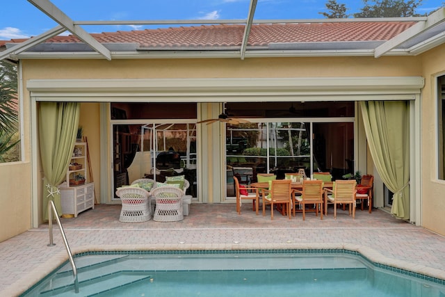 rear view of house with a patio, ceiling fan, and glass enclosure