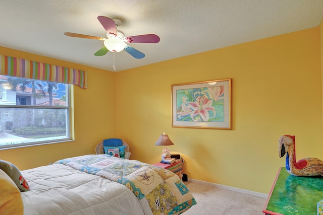 bedroom featuring ceiling fan, light tile patterned flooring, and a textured ceiling