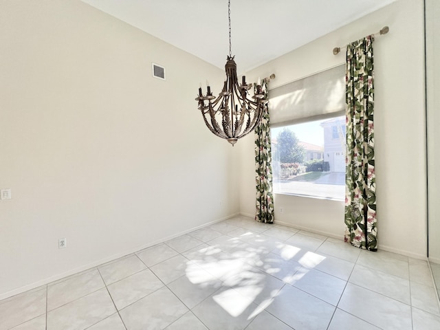 spare room with light tile patterned flooring and a chandelier