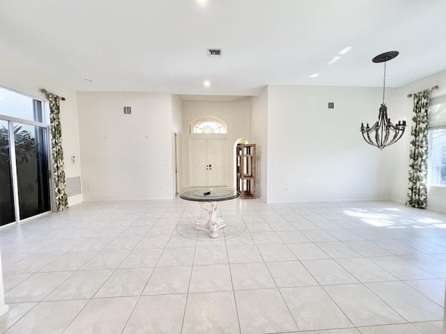 tiled entrance foyer featuring a healthy amount of sunlight and a notable chandelier