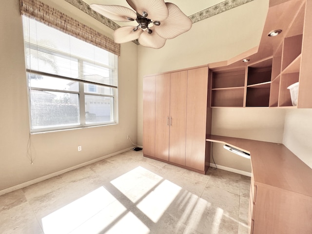 unfurnished bedroom with ceiling fan, built in desk, and a closet