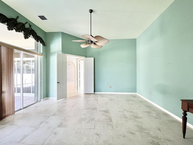 empty room with lofted ceiling, a textured ceiling, and ceiling fan