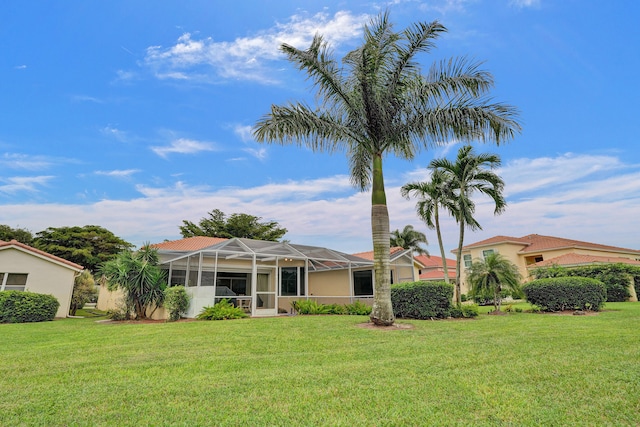 back of house featuring a lawn and a lanai