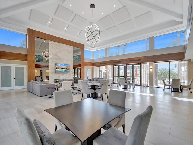 dining room with a towering ceiling, coffered ceiling, a fireplace, and french doors