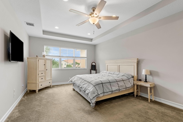 carpeted bedroom featuring ceiling fan, a raised ceiling, and a textured ceiling