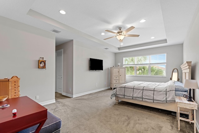 bedroom with carpet flooring, a tray ceiling, and ceiling fan