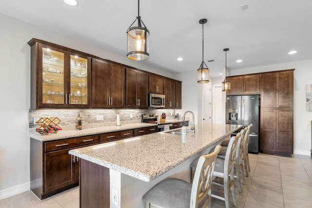 kitchen with sink, pendant lighting, appliances with stainless steel finishes, and a kitchen island with sink