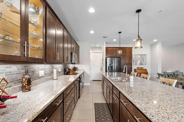 kitchen featuring tasteful backsplash, sink, stainless steel appliances, pendant lighting, and a breakfast bar