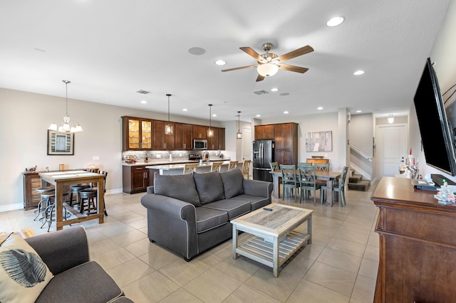 tiled living room with ceiling fan with notable chandelier