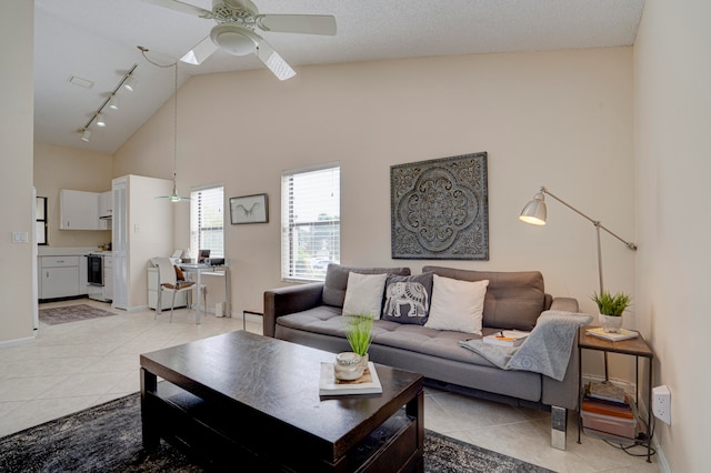 tiled living room with ceiling fan, rail lighting, and high vaulted ceiling