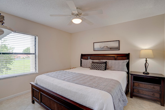 bedroom featuring multiple windows, ceiling fan, light tile patterned floors, and a textured ceiling