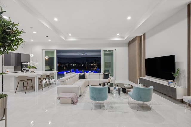 living room featuring a raised ceiling, ornamental molding, and sink