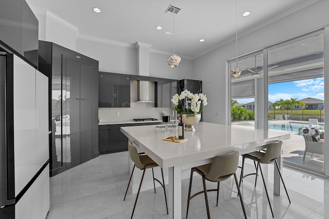 kitchen with wall chimney exhaust hood, a kitchen bar, decorative light fixtures, and white refrigerator