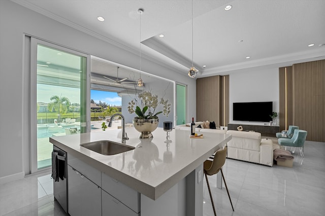 kitchen with sink, an island with sink, decorative light fixtures, gray cabinets, and ornamental molding