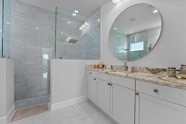 bathroom with a tile shower, vanity, and tile patterned floors