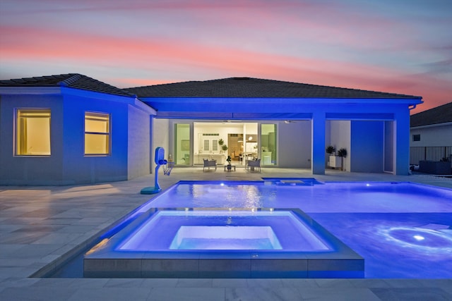 pool at dusk with a patio, an in ground hot tub, and ceiling fan