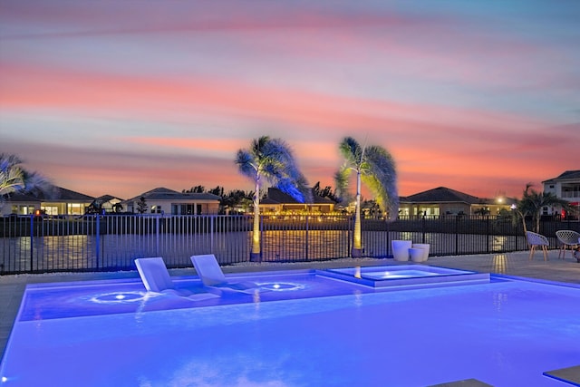 pool at dusk featuring an in ground hot tub