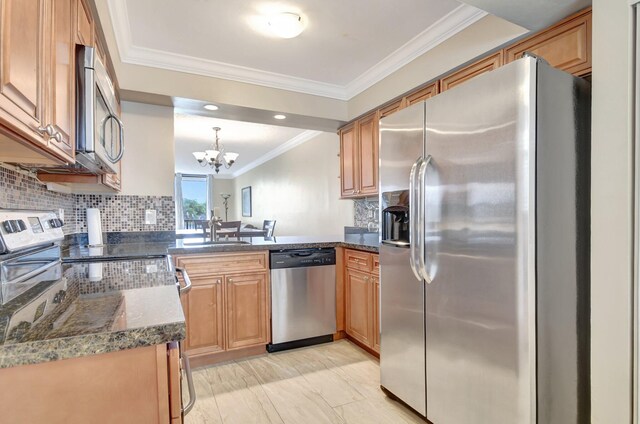 kitchen featuring dark stone counters, ornamental molding, sink, a notable chandelier, and appliances with stainless steel finishes