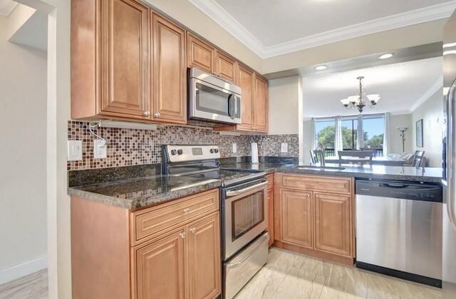 kitchen featuring sink, crown molding, an inviting chandelier, appliances with stainless steel finishes, and tasteful backsplash