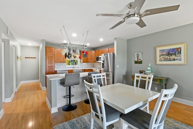 dining space with sink, ceiling fan, and light hardwood / wood-style flooring