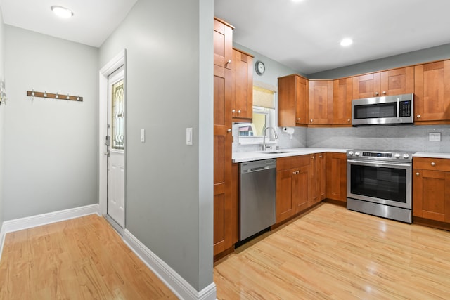 kitchen with light hardwood / wood-style floors, stainless steel appliances, tasteful backsplash, and sink